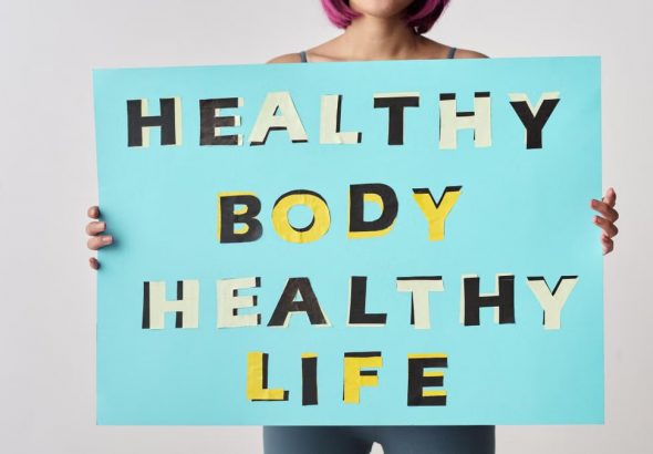 A woman holds a motivational poster advocating a healthy body and life for wellness.