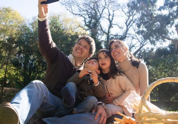 Happy family taking a selfie during a sunny picnic in a park.