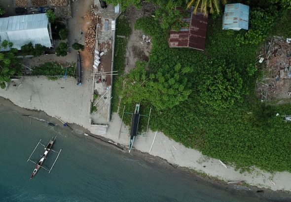 Drone shot capturing a coastal scene with boats and greenery in Una-Una, Indonesia.